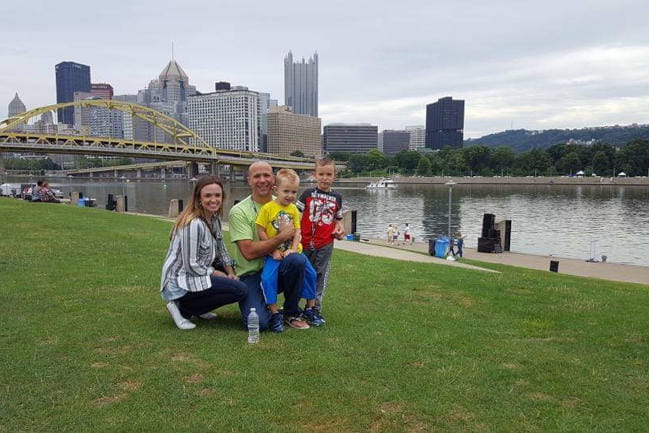 Kira, Chris, Chase, and Vinny Talerico pose in a family photo in front of a city skyline.