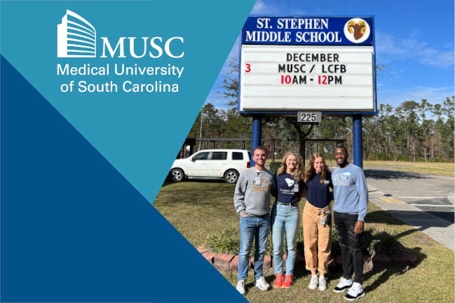 Four MUSC medical students pose in front of sign for Saint Stephen Middle School. The students help provide community outreach.
