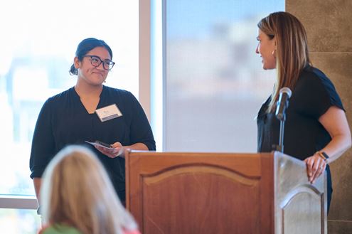 Two women engaged in conversation at a podium, sharing ideas and insights in a professional setting. 