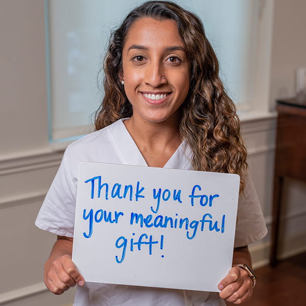 MUSC Nursing student and scholarship recipient with sign reading Thank you for your meaningful gift