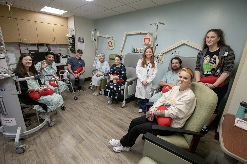 Eight patients, some holding red kidney shaped pillows, and a doctor smile while gathered in a room.